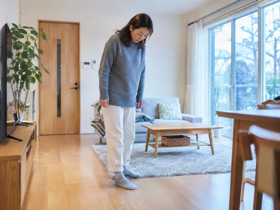 冬、寒さに身をすくめてリビングに立つ女性